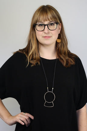 Betsy & iya 14k gold-plated Novi hoop earrings, styled on a model with a betsy & iya yellow bronze and cotton Yoso necklace and a black tunic.