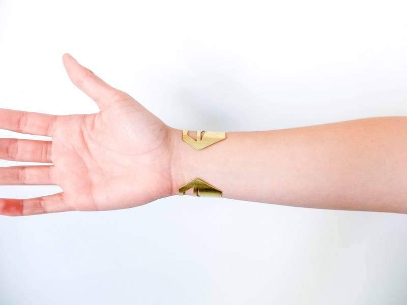 The back of the bold, modern, and adjustable brass Ravenel cuff bracelet, worn snugly on the wrist of a betsy & iya model.