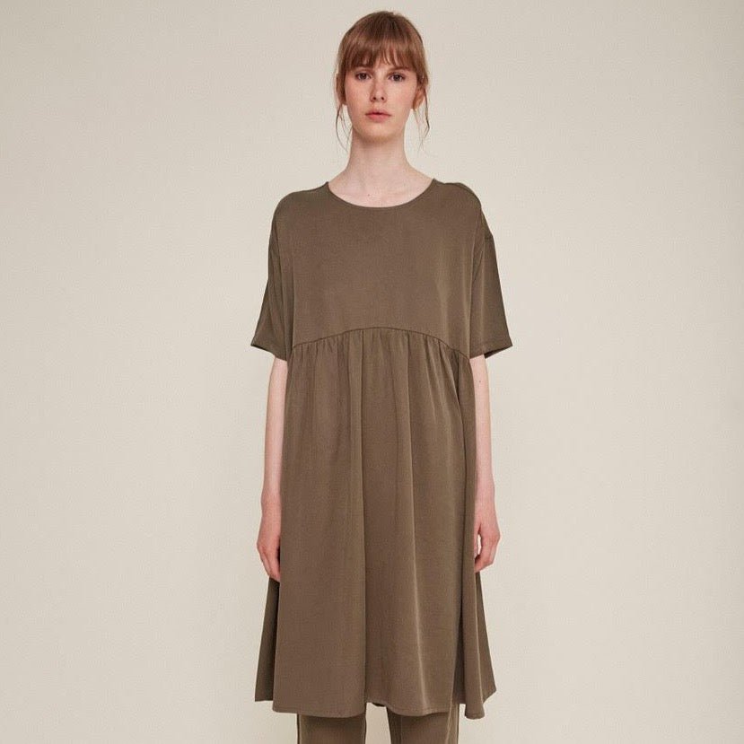 Red-haired woman wears a brown babydoll dress and matching pants. The Drapey Dress in Kaki is from designer Rita Row.