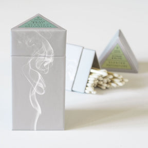 Two triangular boxes against a white background. One is upright and the other is open and laying on its side. The Prism Scented matches are from designer Skeem and made in the USA.