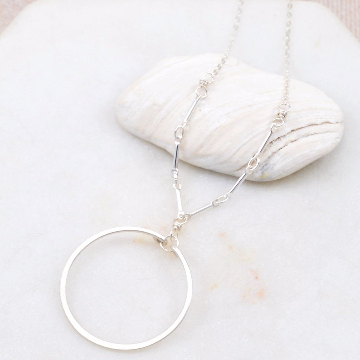 A single silver hoop is suspended from silver links and a silver chain. The Single Circle Necklace in Silver is designed by Amy Olson and handmade in Portland, Oregon.