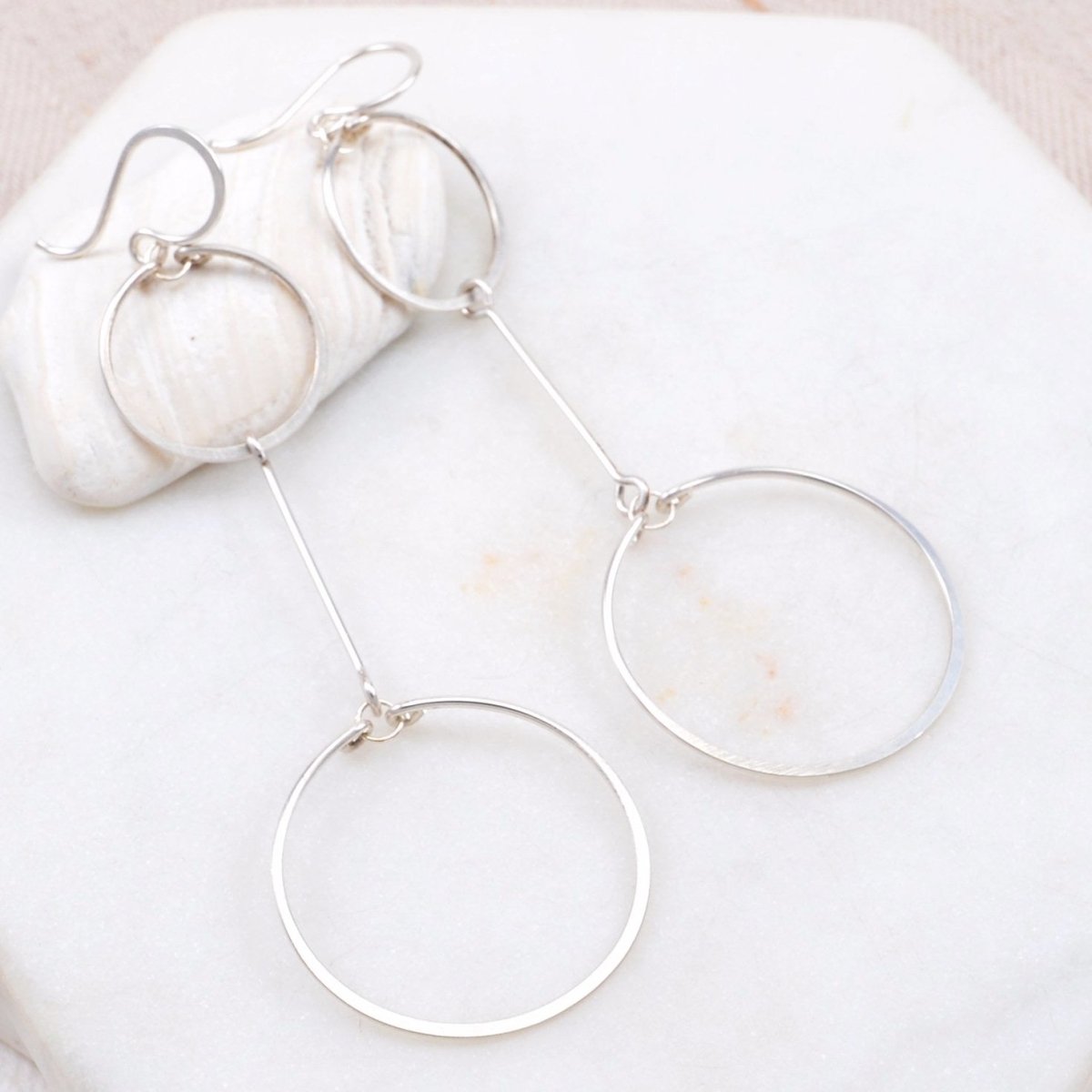 Two hand forged and hammered silver circles come together with a gold bar in between. The Double Circle Drop Earrings in Silver are designed and handmade by Amy Olson in Portland, Oregon.