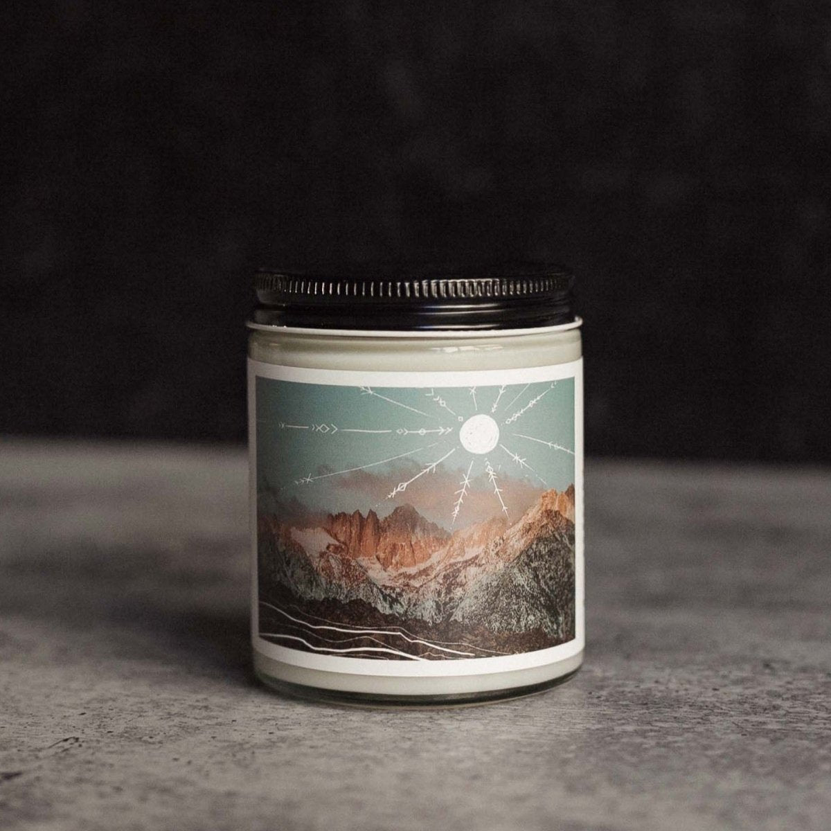 Clear glass jar candle with a black lid and mountain landscape artwork. The Terra Jar Candle is hand-poured by Particle Goods in Seattle, WA.