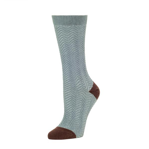 A grey-blue sock with a herringbone pattern stands against a white background. The heel and toe of the sock are brown. The Chunky Knit Herringbone Crew Sock in Lead is from Zkano, and made in Alabama, USA.